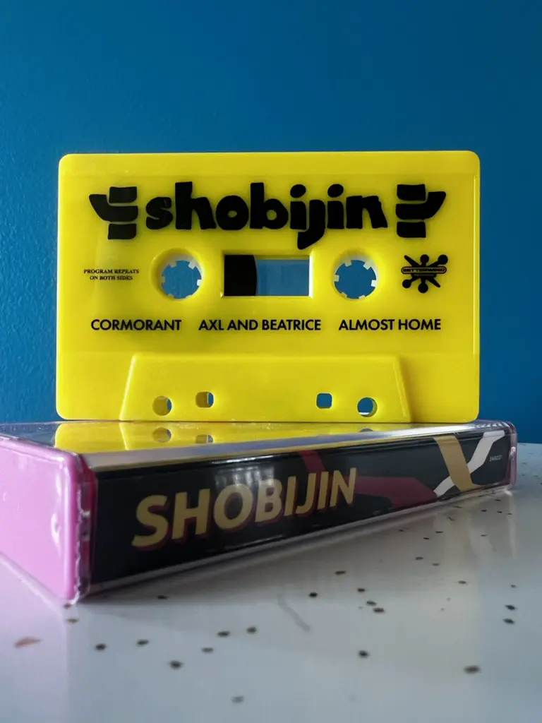 The Shobijin cassette tape stacked on top of its case.