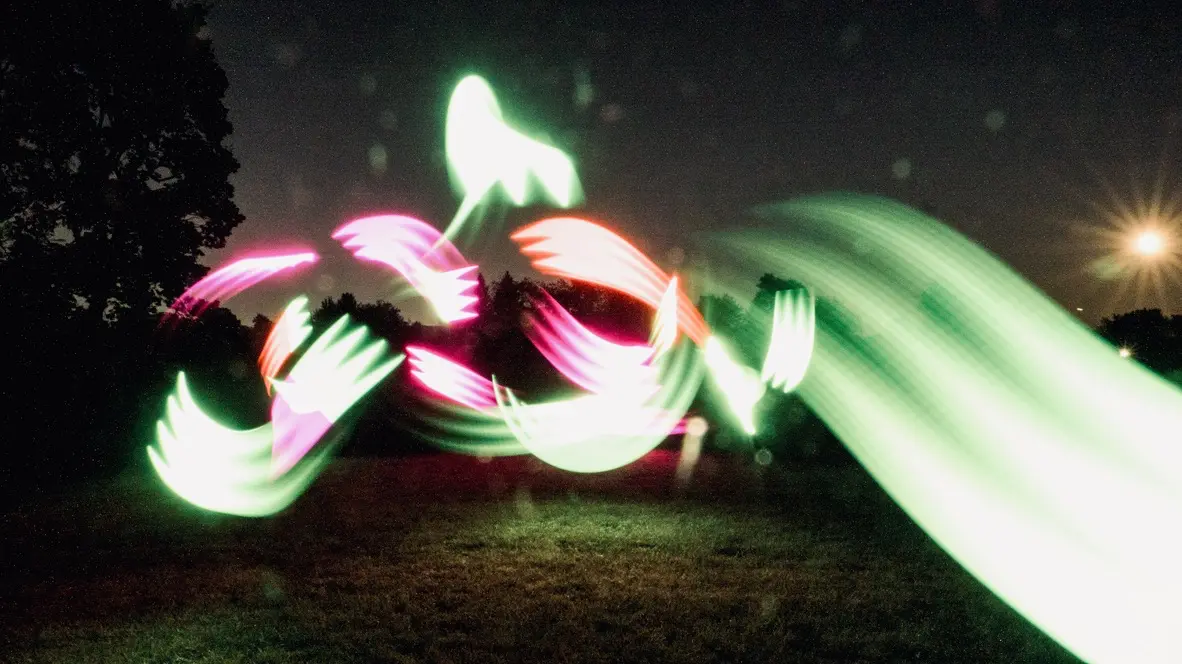 Experimental photograph with psychedelic, colorful shapes in a field outdoors at night.